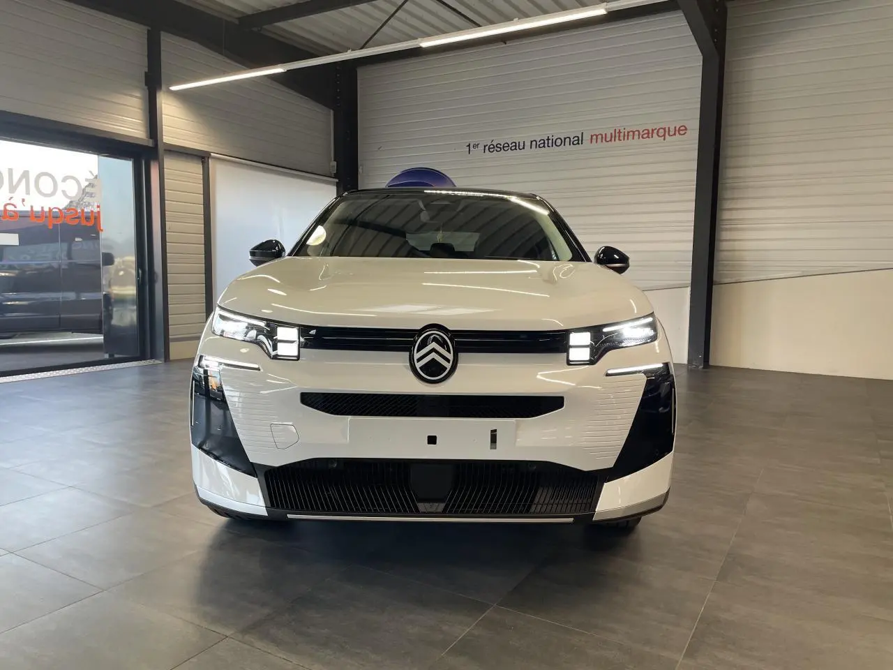 Vue avant d'un Citroën C5 Aircross blanc Okenite avec toit noir, calandre et phares LED distinctifs en showroom.