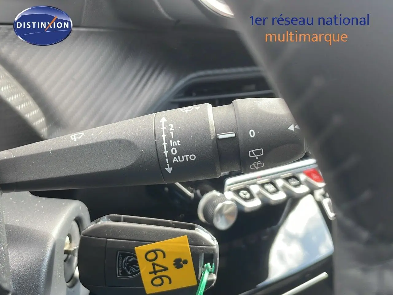 Gros plan sur la commande d'essuie-glace et la clé Peugeot dans l'habitacle noir du 2008 2025.