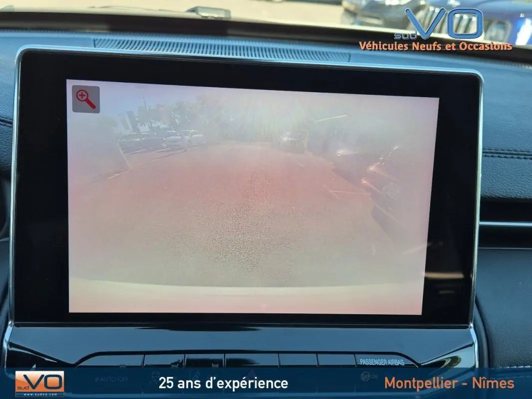 Écran tactile intérieur montrant la caméra de recul du Jeep Compass blanc, tableau de bord noir moderne.