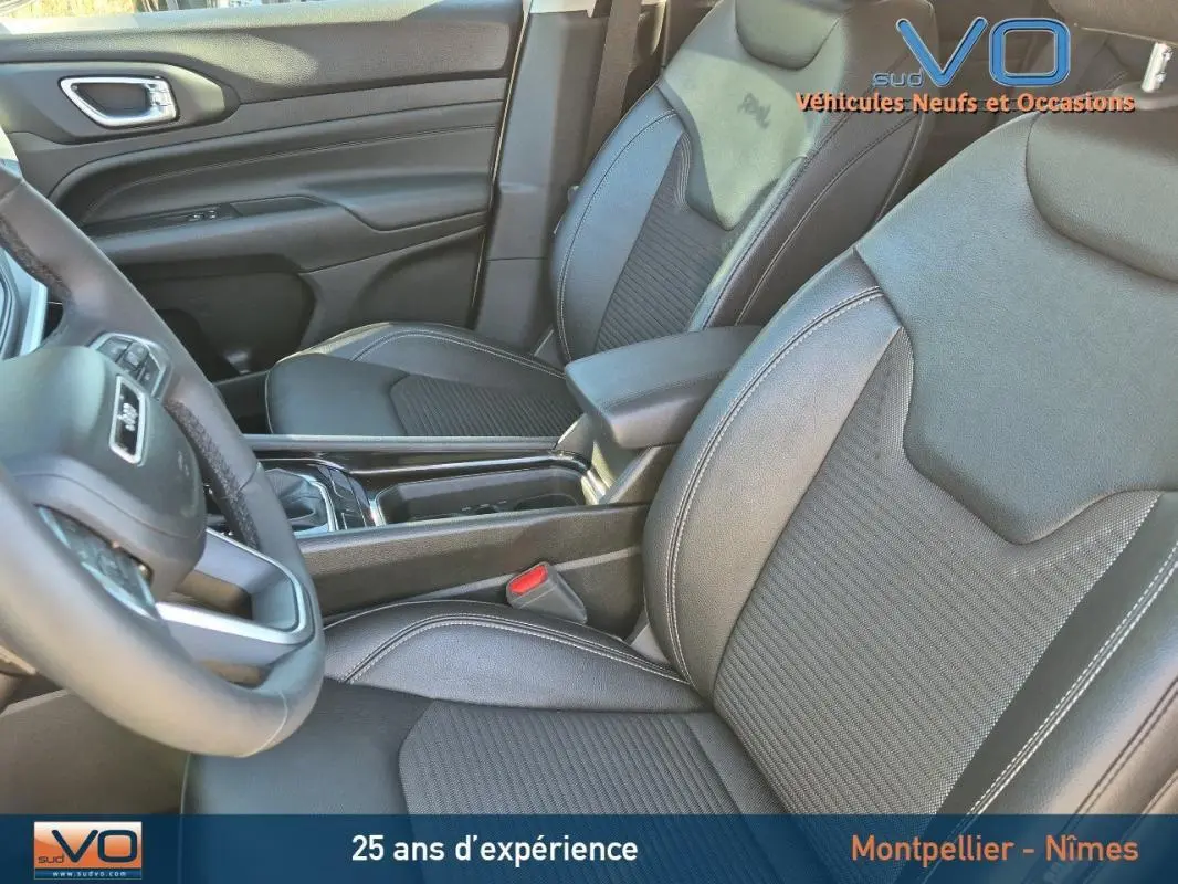 Vue intérieure rapprochée des sièges avant en cuir noir du Jeep Compass 2023 avec accoudoir central et volant partiel visible.