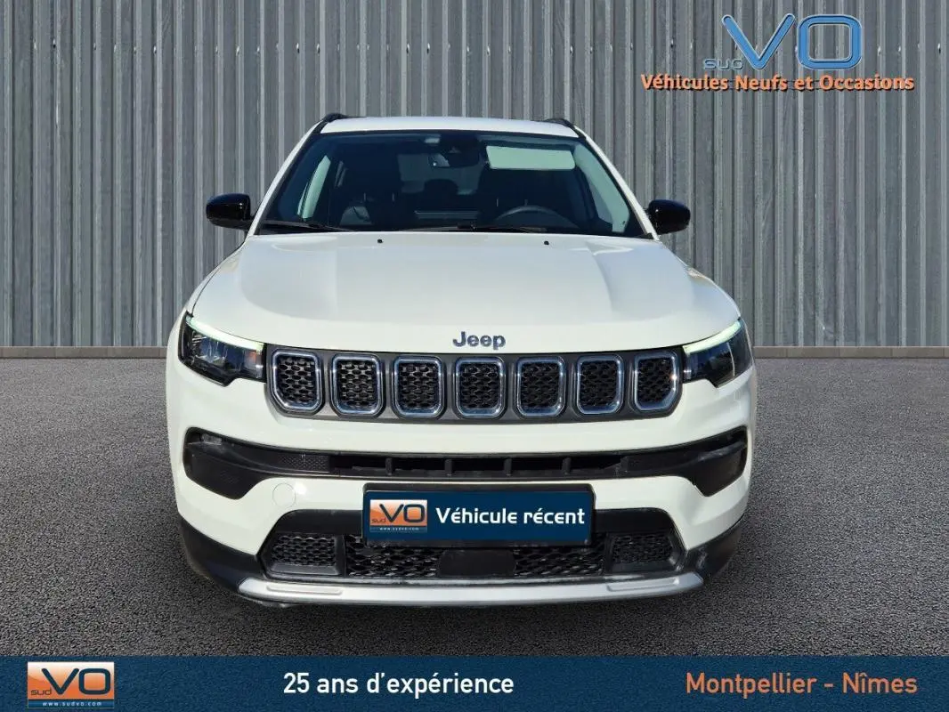 Vue frontale d'un Jeep Compass blanc 2023 avec calandre à sept fentes et phares LED allumés.