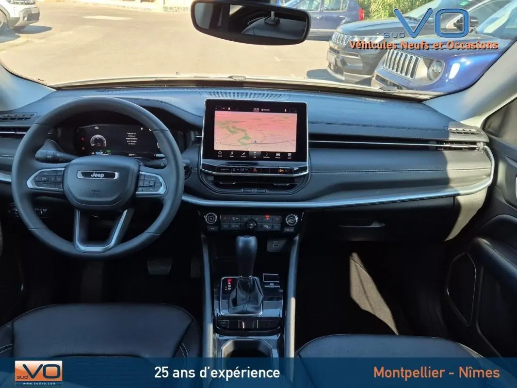 Vue intérieure frontale du tableau de bord noir du Jeep Compass 2023 avec écran tactile central et volant multifonction.