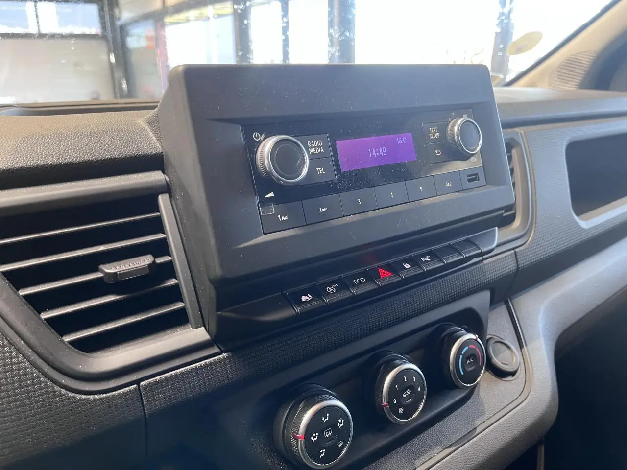 Tableau de bord du Renault Trafic Fourgon 2023, vue rapprochée de la console centrale avec radio et commandes climatisation.