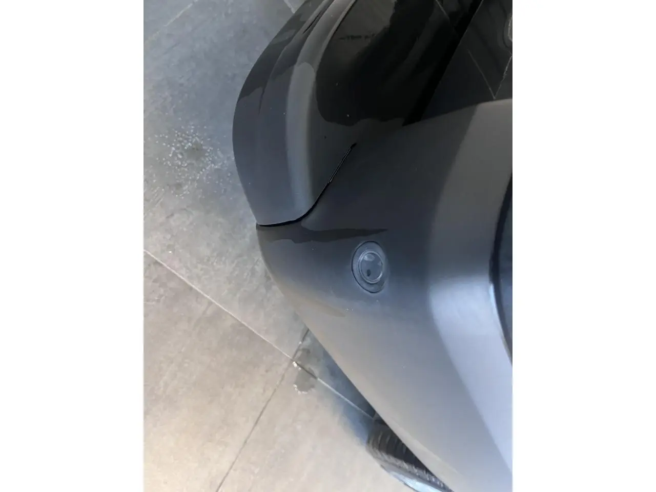 Détail du bouclier avant gris foncé du Renault Trafic Fourgon vu de dessus, avec capteur de stationnement visible.