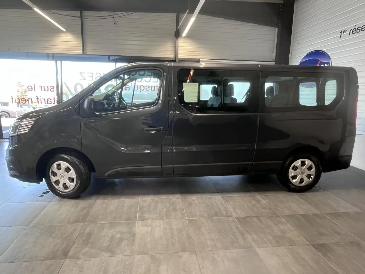 Vue de profil côté gauche du Renault Trafic Fourgon gris foncé, avec vitres latérales teintées et roues 16 pouces.
