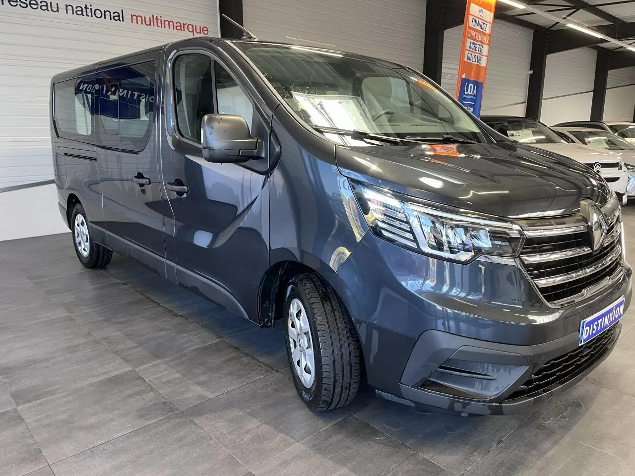 Vue 3/4 avant gauche d'un Renault Trafic Fourgon gris foncé avec projecteurs Full LED et vitres teintées.