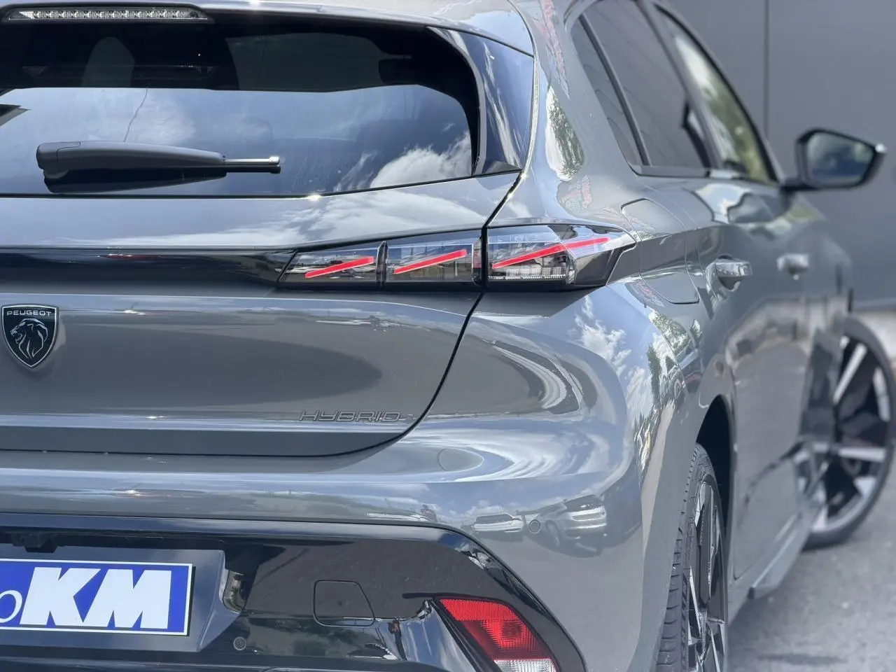 Vue 3/4 arrière droite d'une Peugeot 308 gris Selenium avec feux arrière LED en forme de griffes et jantes alliage bi-tons.