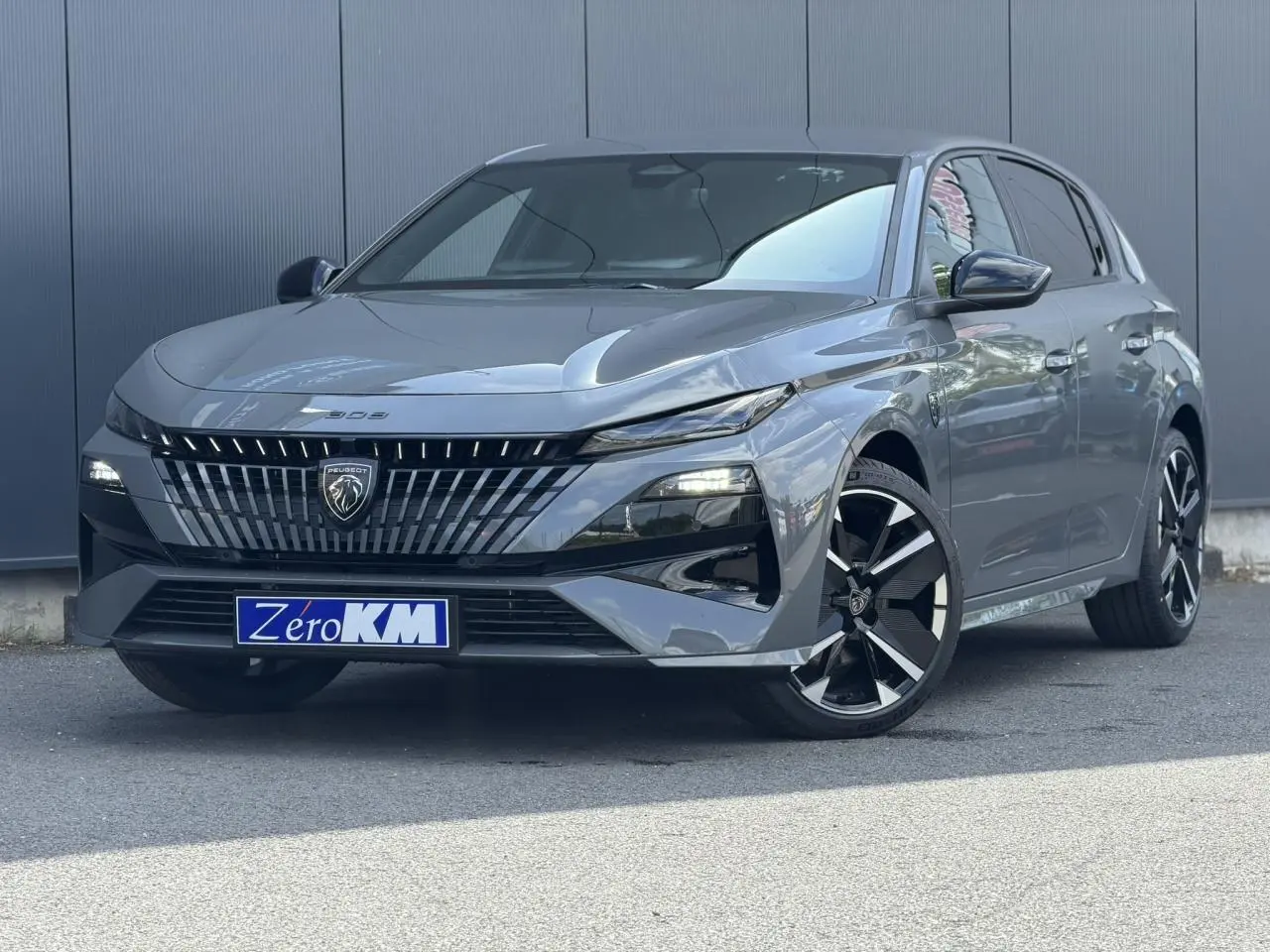 Peugeot 308 gris Selenium vue 3/4 avant droit, calandre noire distinctive et jantes alliage bi-ton.