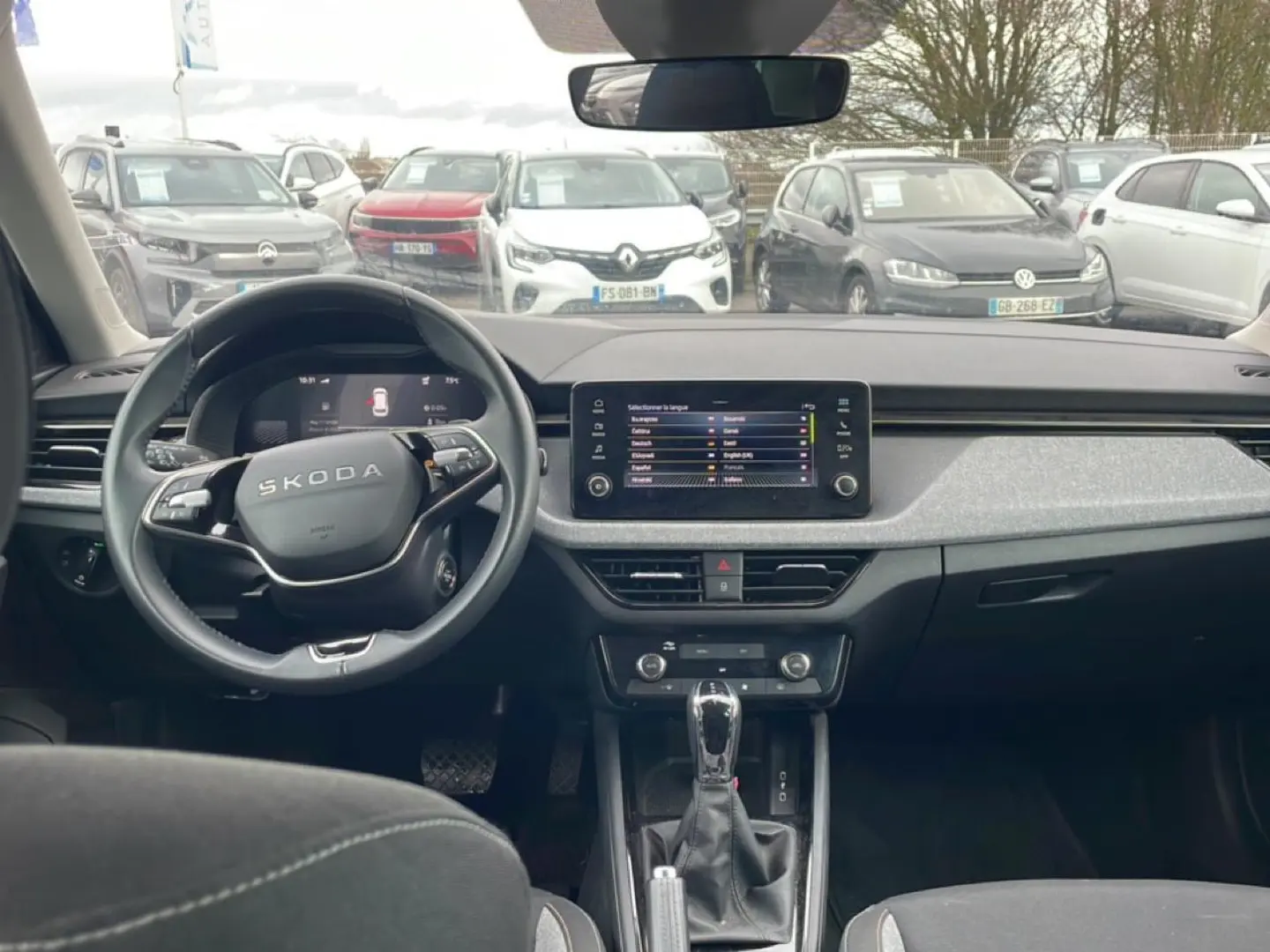 Vue intérieure avant du Skoda Kamiq 2025 avec tableau de bord noir et écran tactile central allumé.