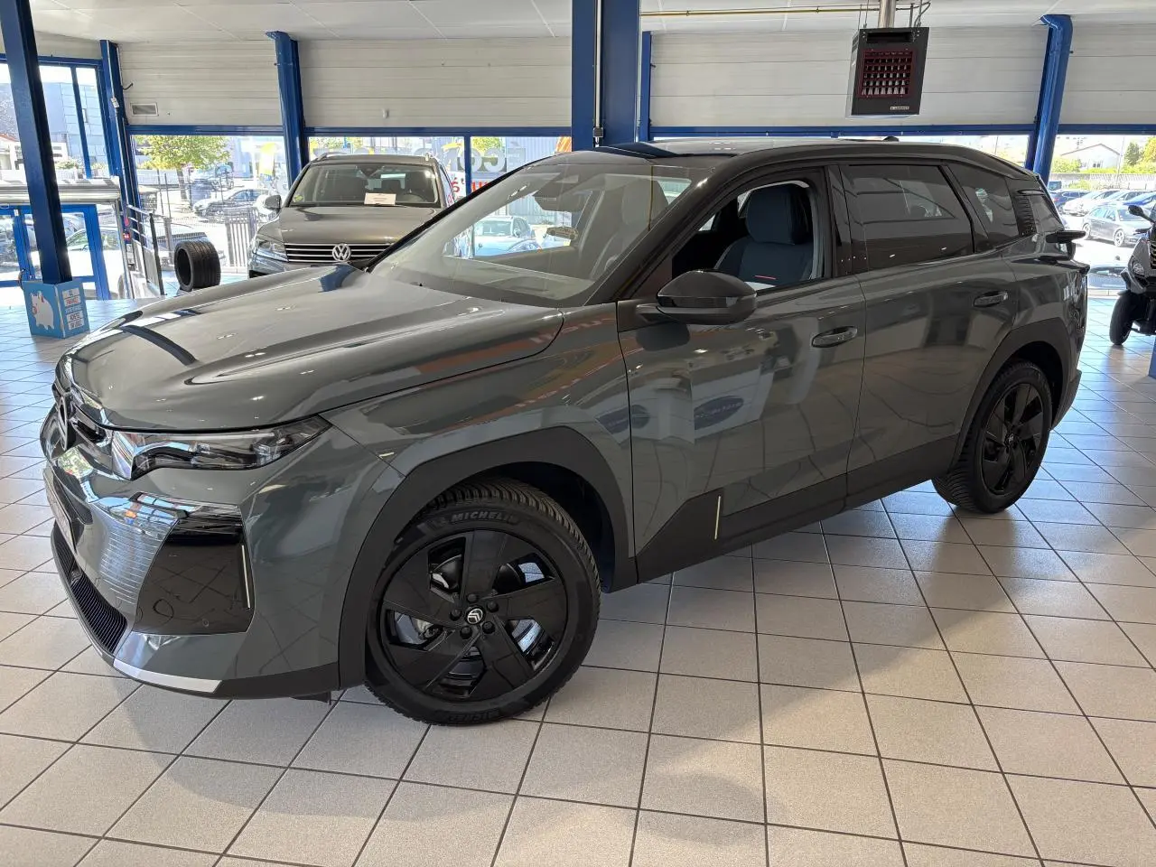 Vue 3/4 avant droite du Citroën C5 Aircross vert métallisé avec jantes alliage noires en showroom.