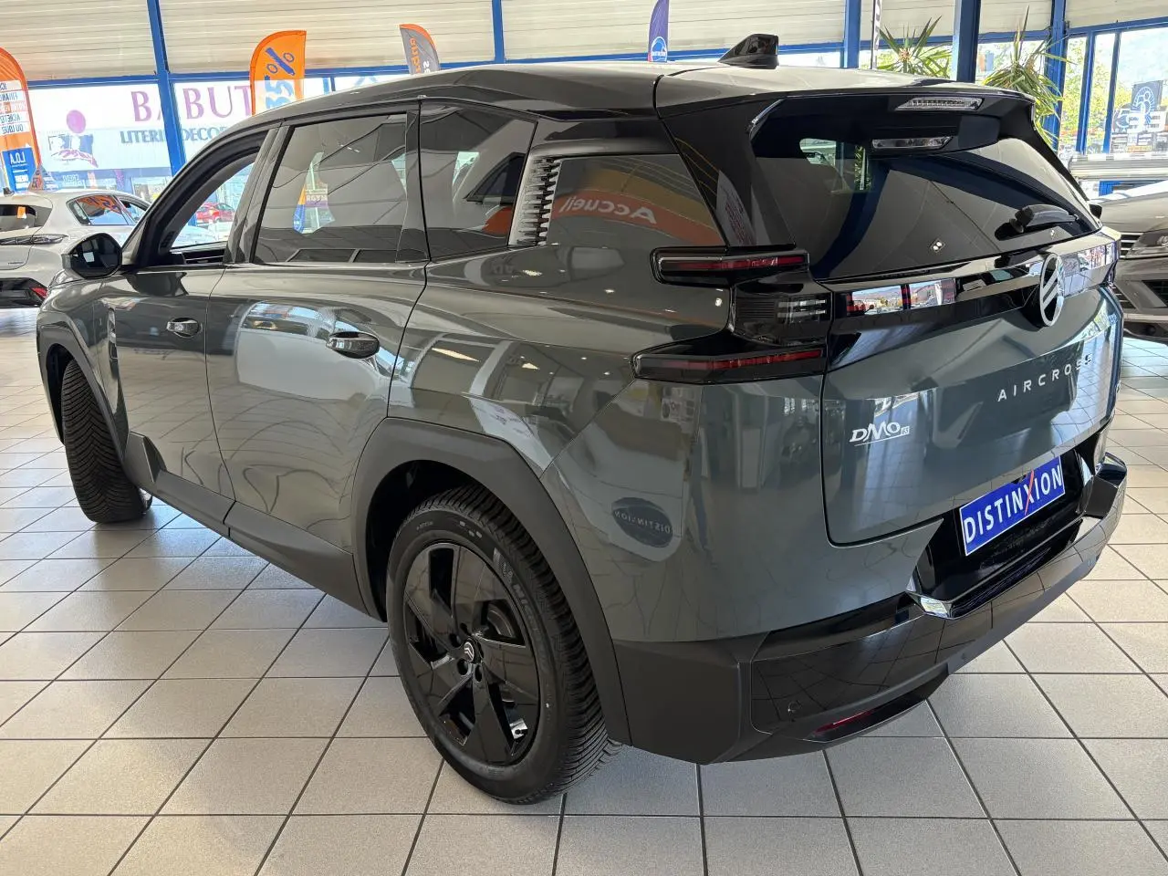 Vue 3/4 arrière droite du Citroën C5 Aircross vert métallisé avec jantes noires et feux arrière LED 3D en intérieur showroom.