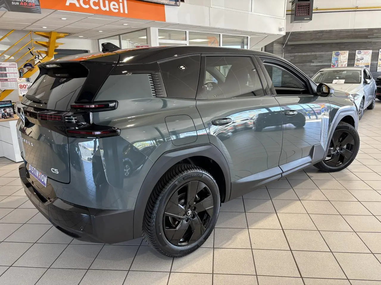 Vue 3/4 arrière droite du Citroën C5 Aircross vert métallisé avec toit noir et jantes alliage noires en showroom.