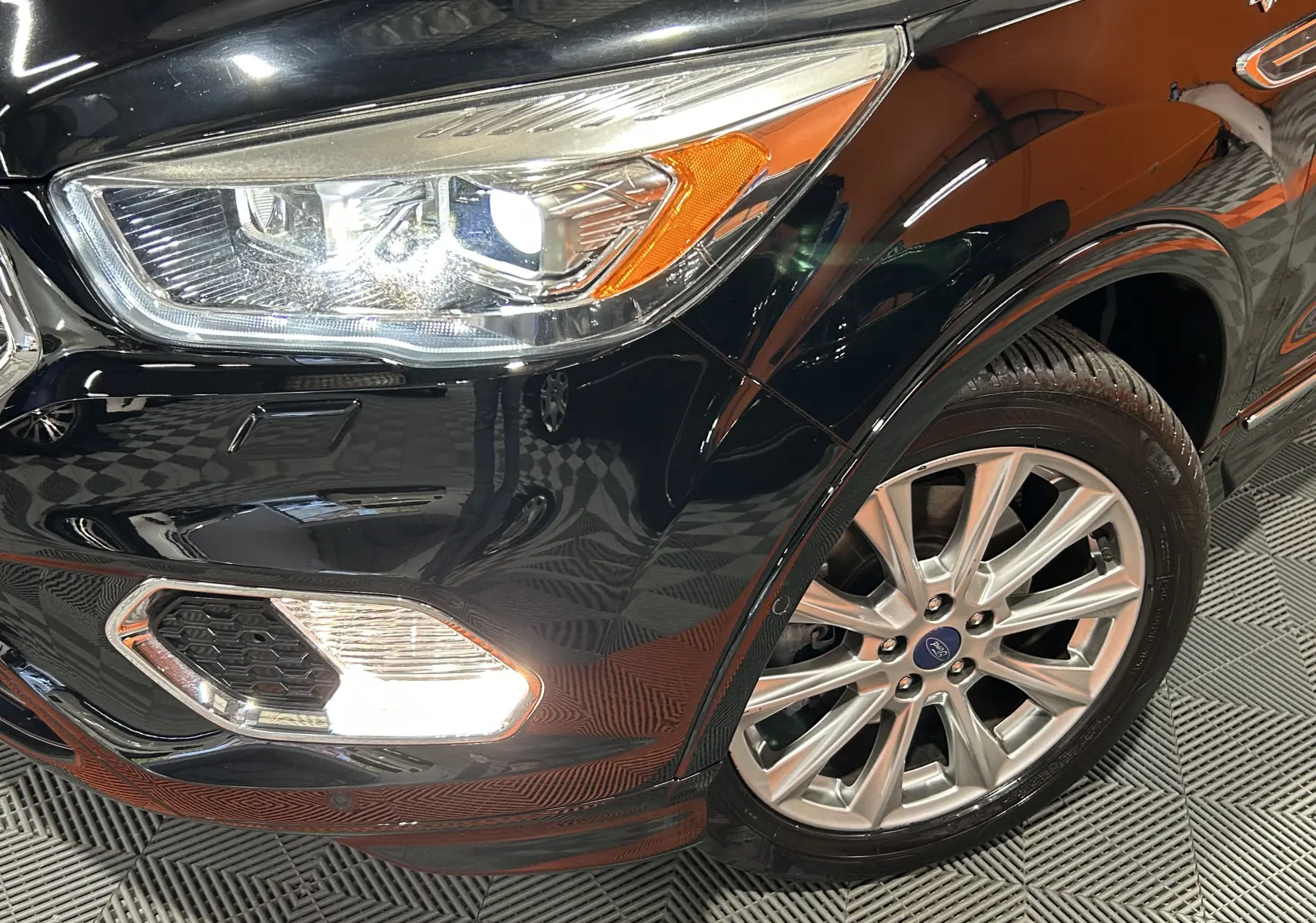 Gros plan sur l’avant droit noir du Ford Kuga 2017, mettant en valeur le phare allumé et la jante en alliage.