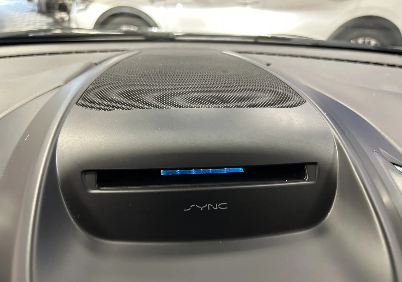 Gros plan sur le haut de la planche de bord noire du Ford Kuga 2017 avec écran SYNC illuminé en bleu.