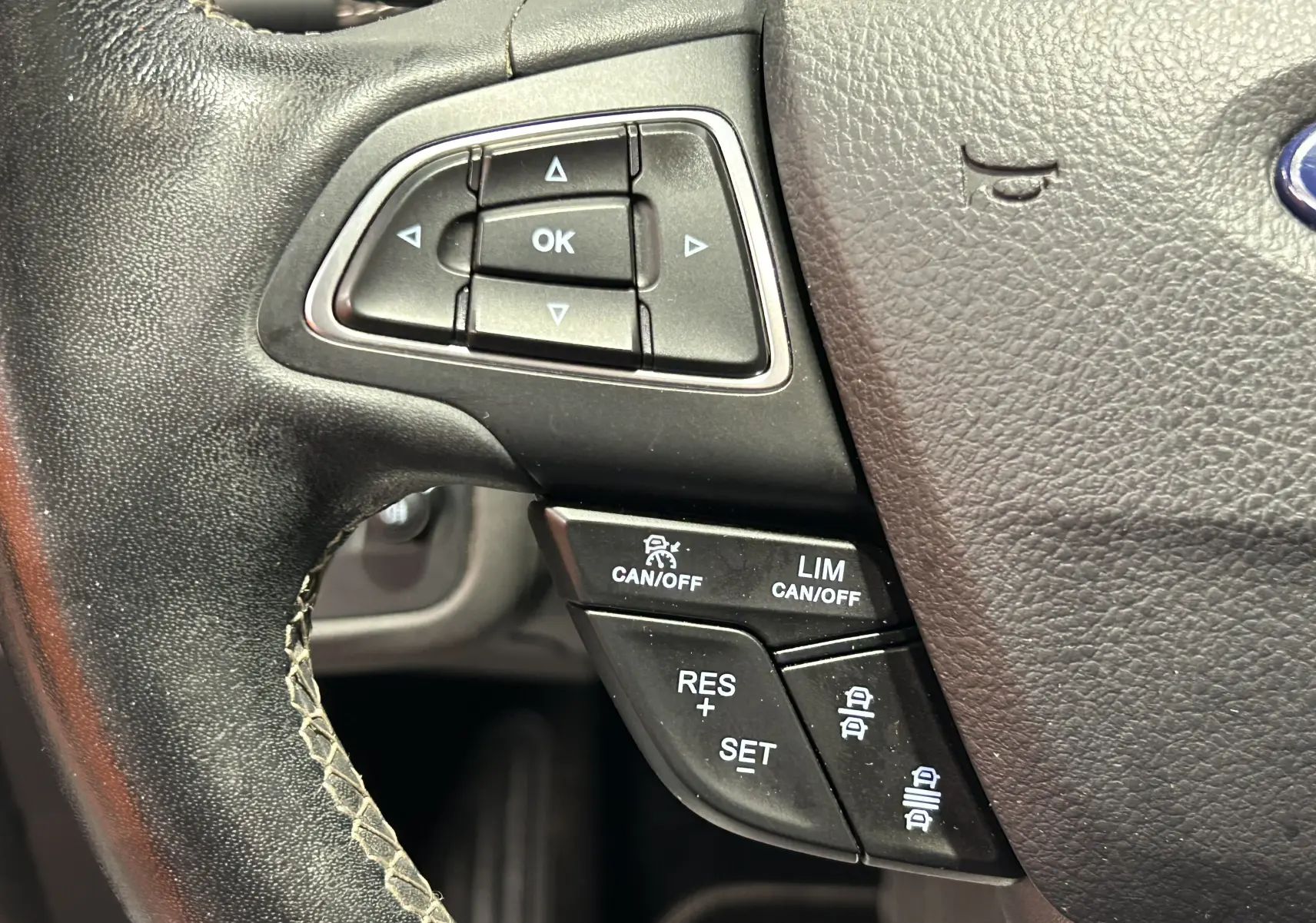 Gros plan sur les commandes multifonctions noires du volant en cuir noir du Ford Kuga 2017, version Vignale.