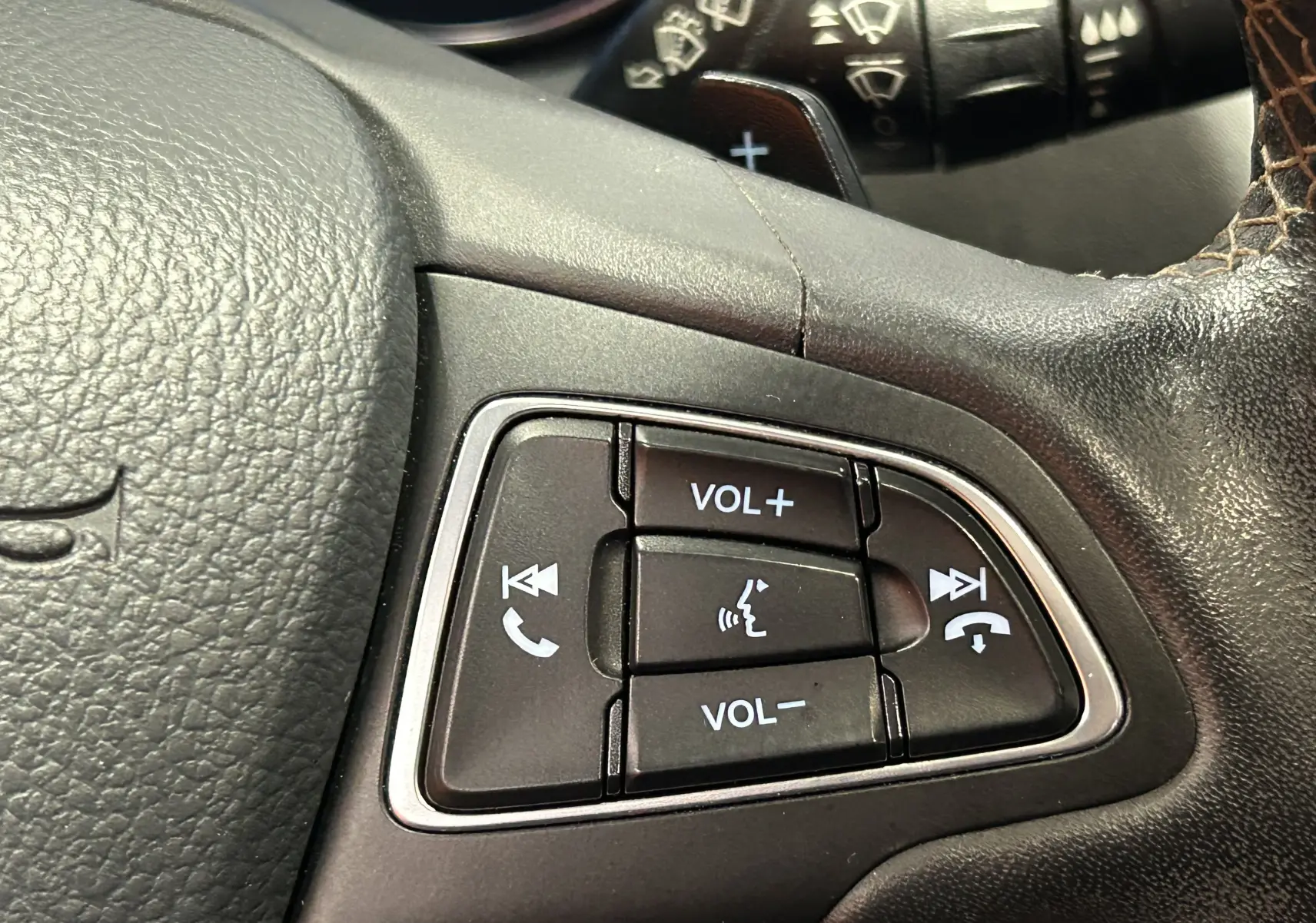 Gros plan sur les commandes audio au volant cuir noir du Ford Kuga TDCI 180 BVA Powershift 4x4 Vignale.