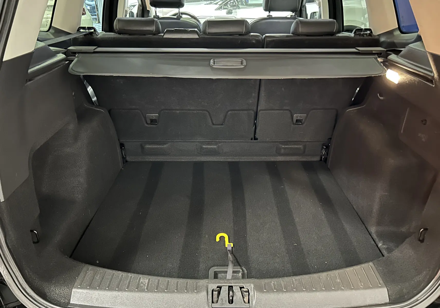 Vue intérieure du coffre noir du Ford Kuga TDCI 180 BVA Powershift 4x4 Vignale, avec cache-bagages déployé.