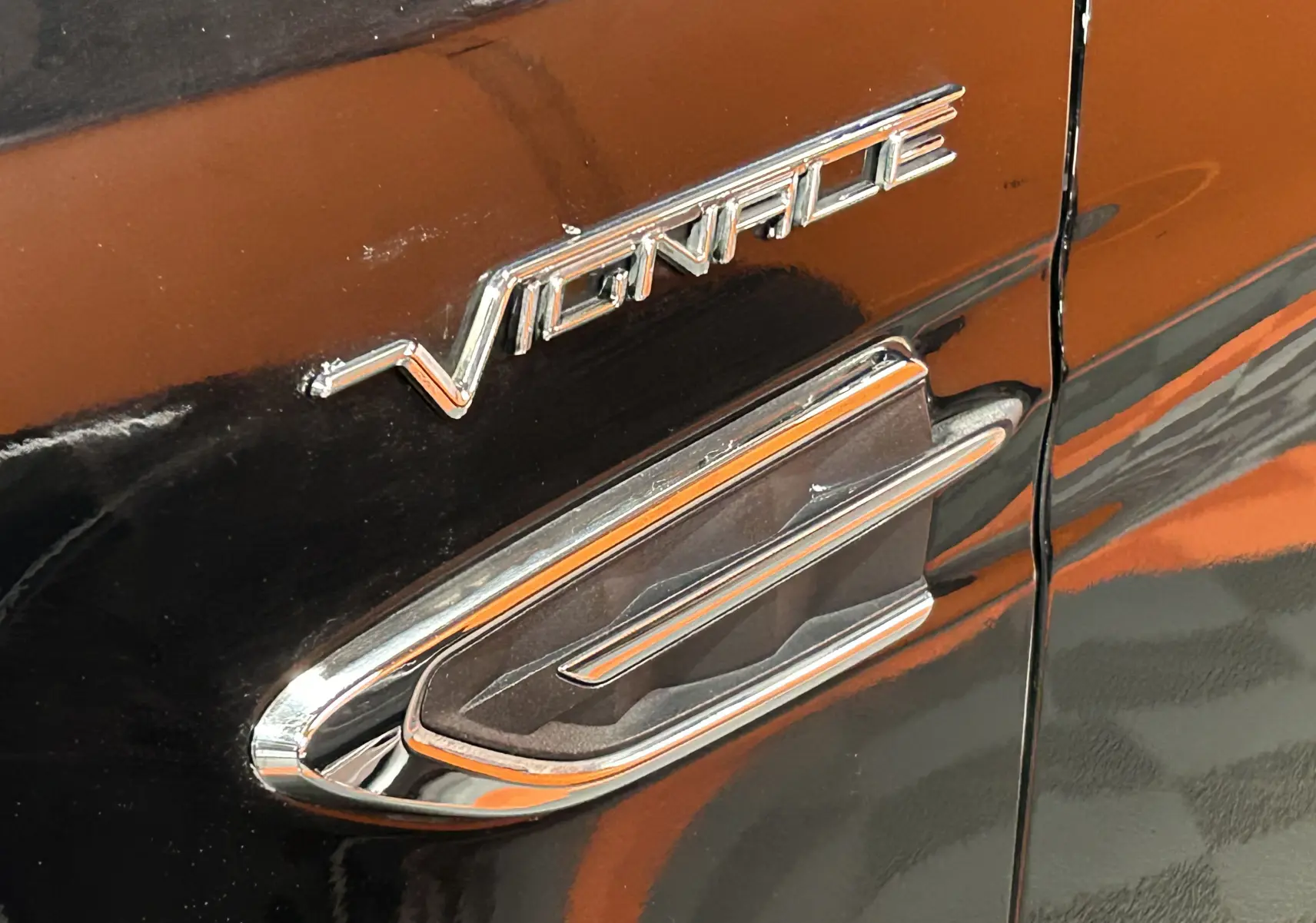 Gros plan sur l’inscription Vignale chromée sur la porte noire d’un Ford Kuga 2017 suréquipé.