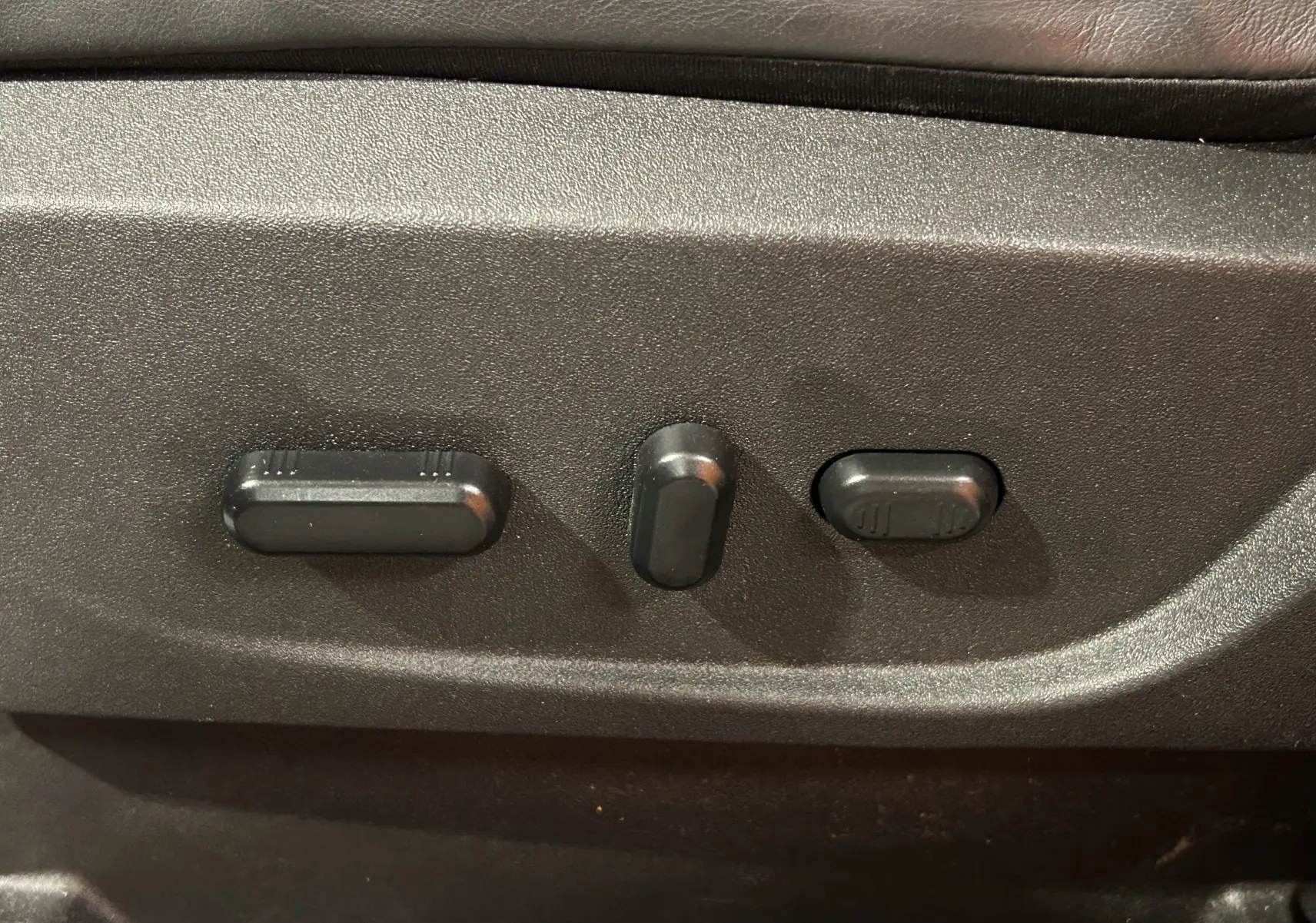 Gros plan sur les commandes électriques de réglage du siège en cuir noir du Ford Kuga TDCI 180 BVA Vignale 2017.