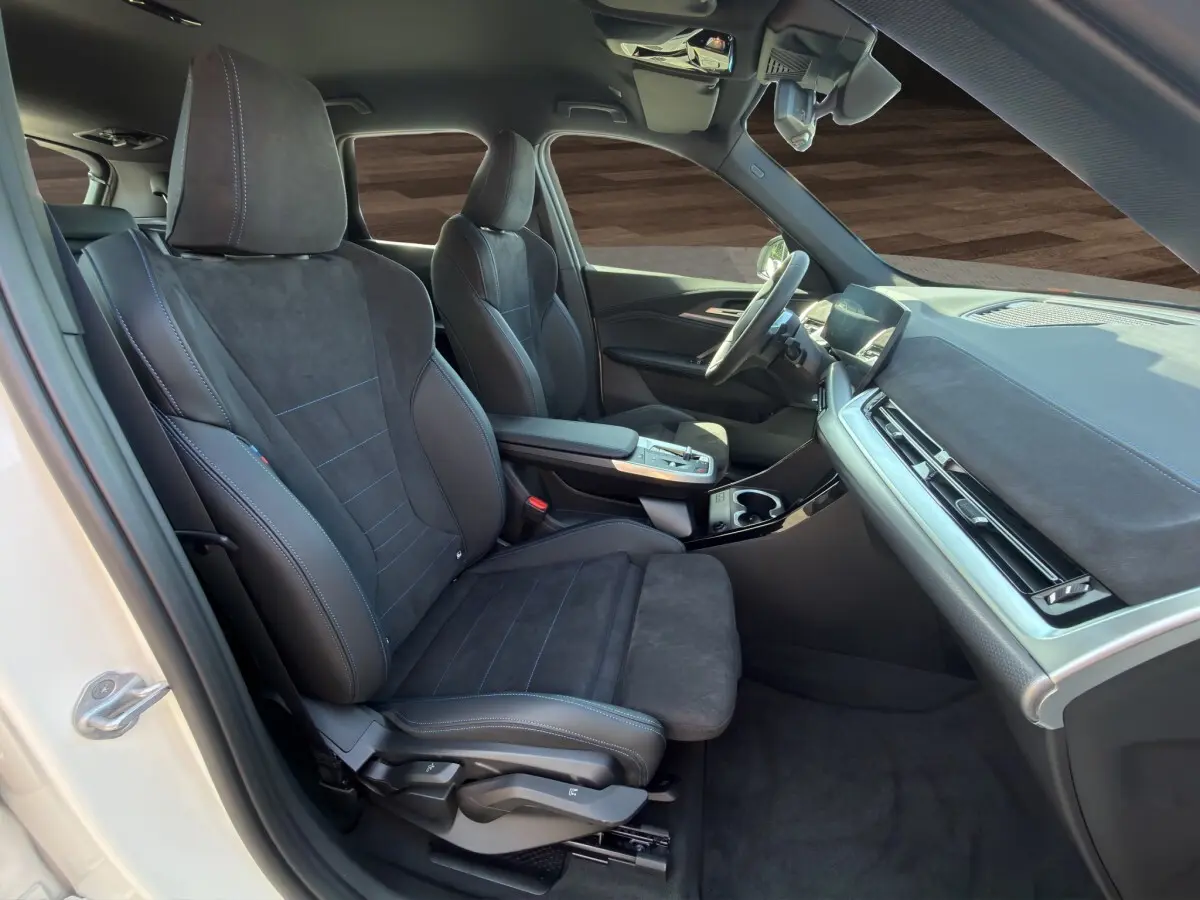 Intérieur avant droit du BMW X1 blanc 2025, sièges sport M Sport en alcantara noir et tableau de bord moderne.