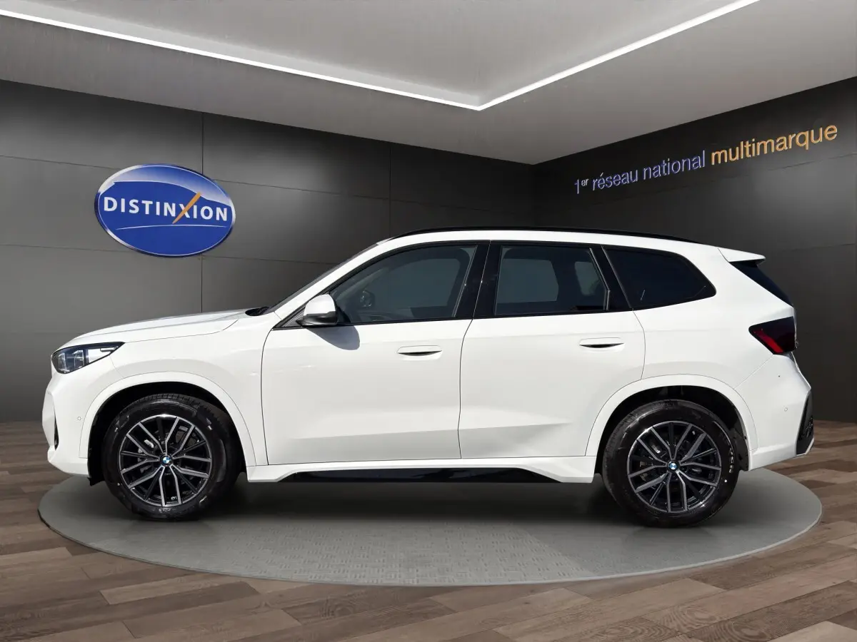 BMW X1 sDrive20d blanc en vue profil gauche, avec jantes noires et toit blanc contrasté.