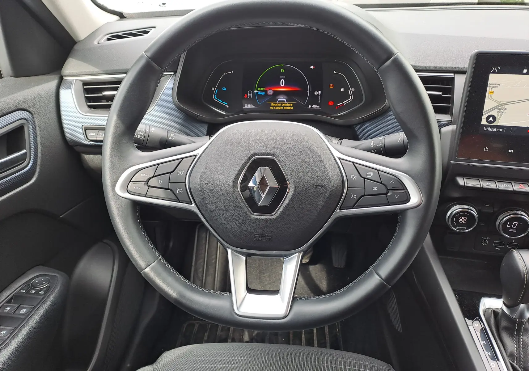 Vue rapprochée du volant noir de la Renault Arkana 2023 avec tableau de bord numérique et écran tactile de navigation.