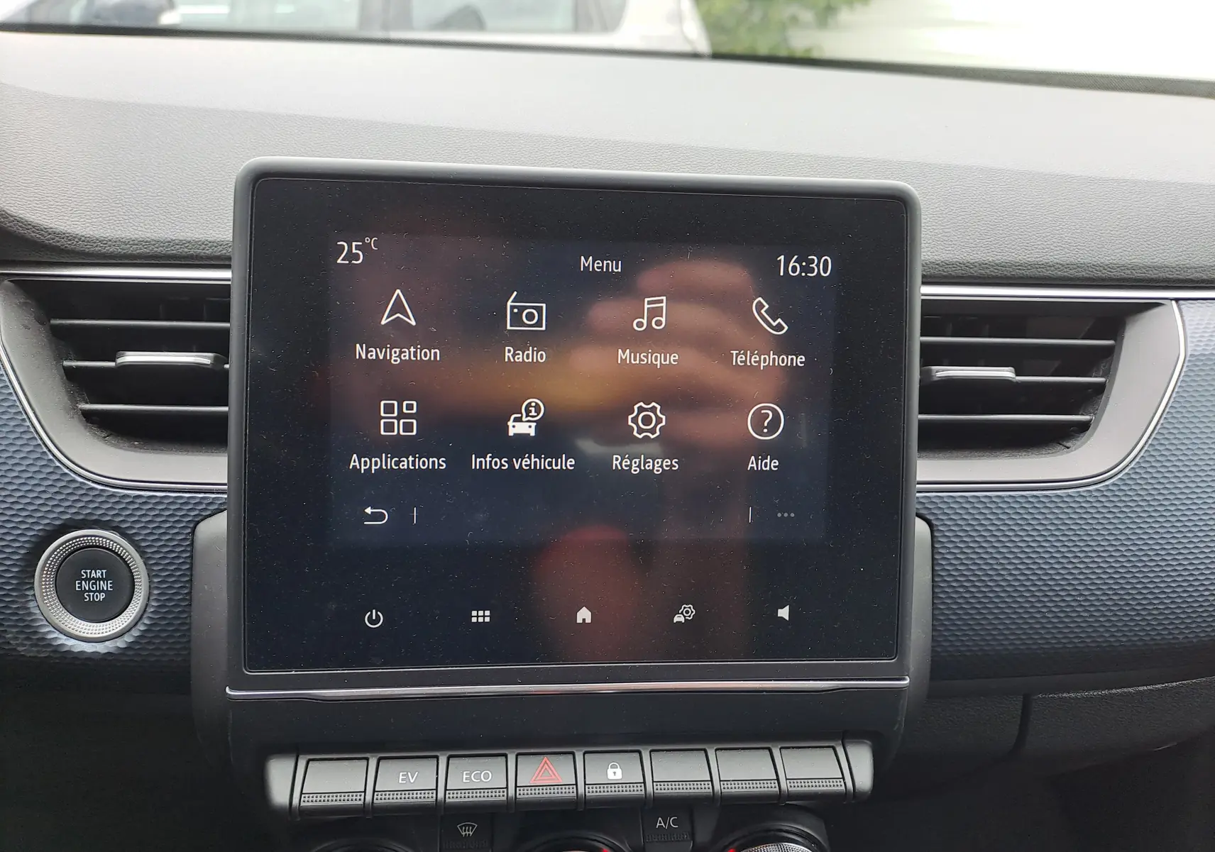 Écran tactile central du tableau de bord du Renault Arkana bleu Zanzibar, avec commandes climatisation et démarrage moteur visible.