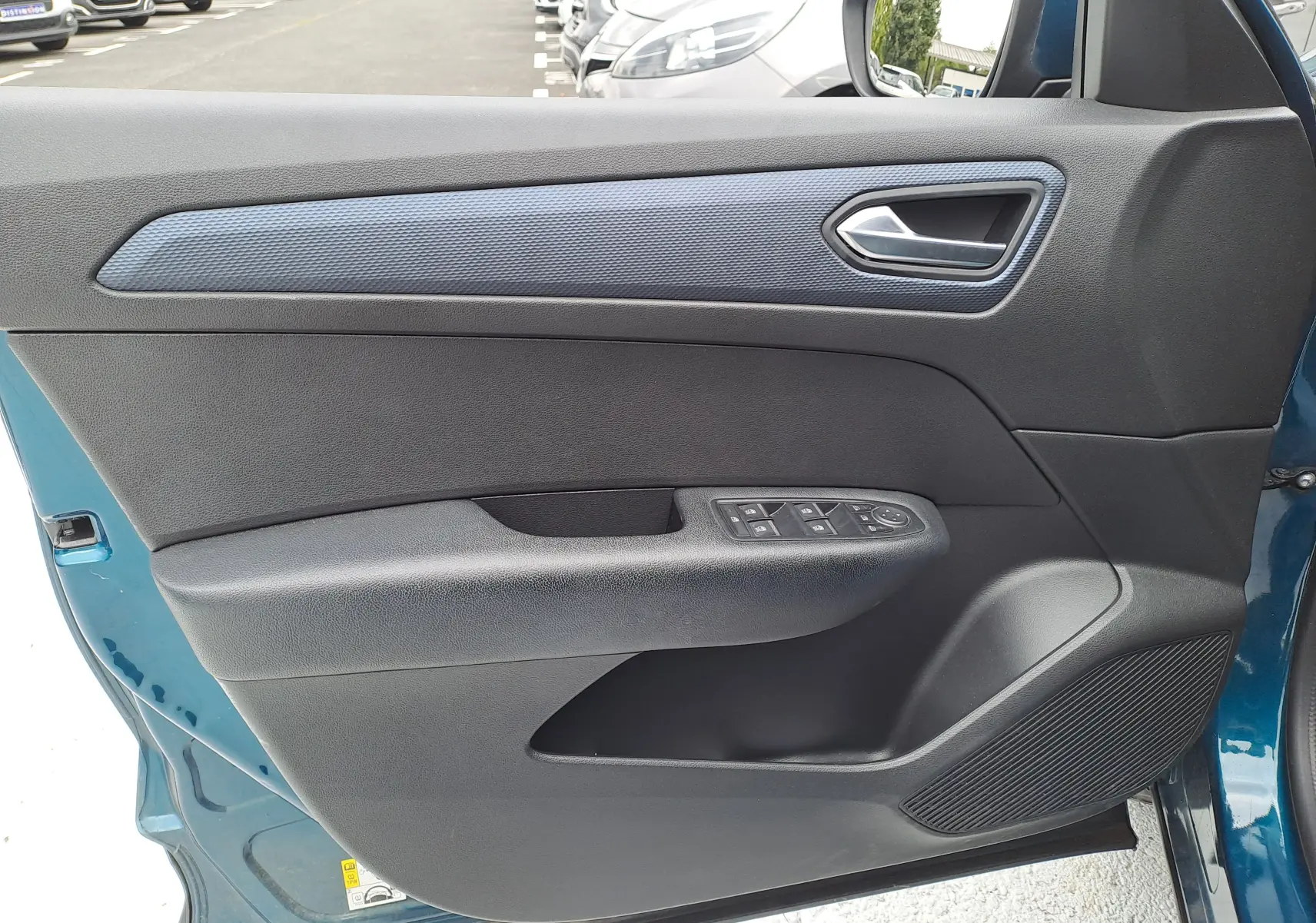 Vue rapprochée de la porte avant gauche bleu Zanzibar métal du Renault Arkana 2023 avec commandes de vitres et haut-parleur intégré.