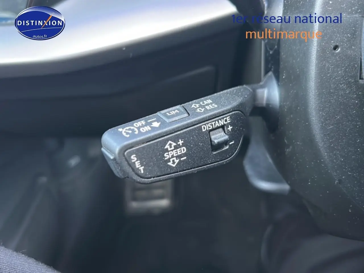 Gros plan sur la commande de régulateur de vitesse au volant d'une Audi A3 Sportback noire 2024.