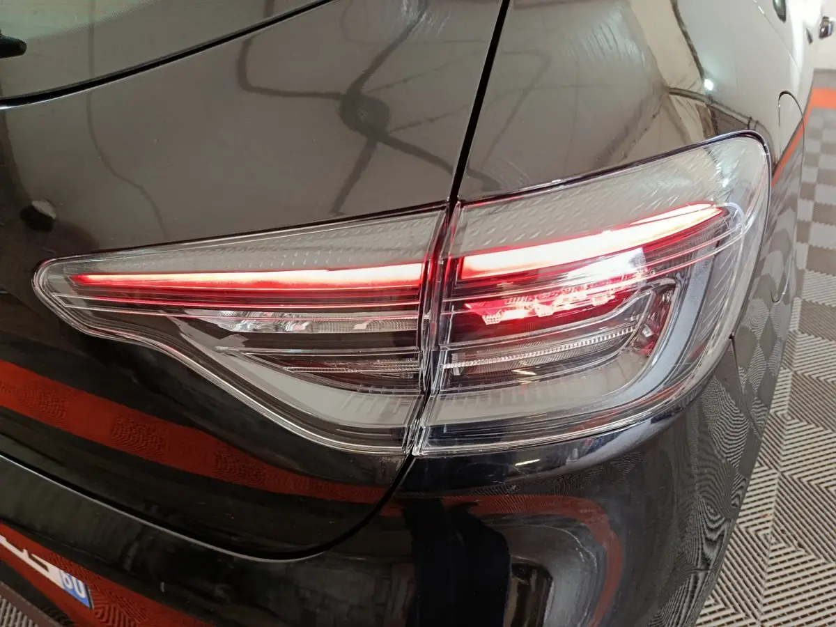 Gros plan sur le feu arrière droit rouge et blanc d'une Renault Clio noire Evolution Blue dCi 100 -25 2025.