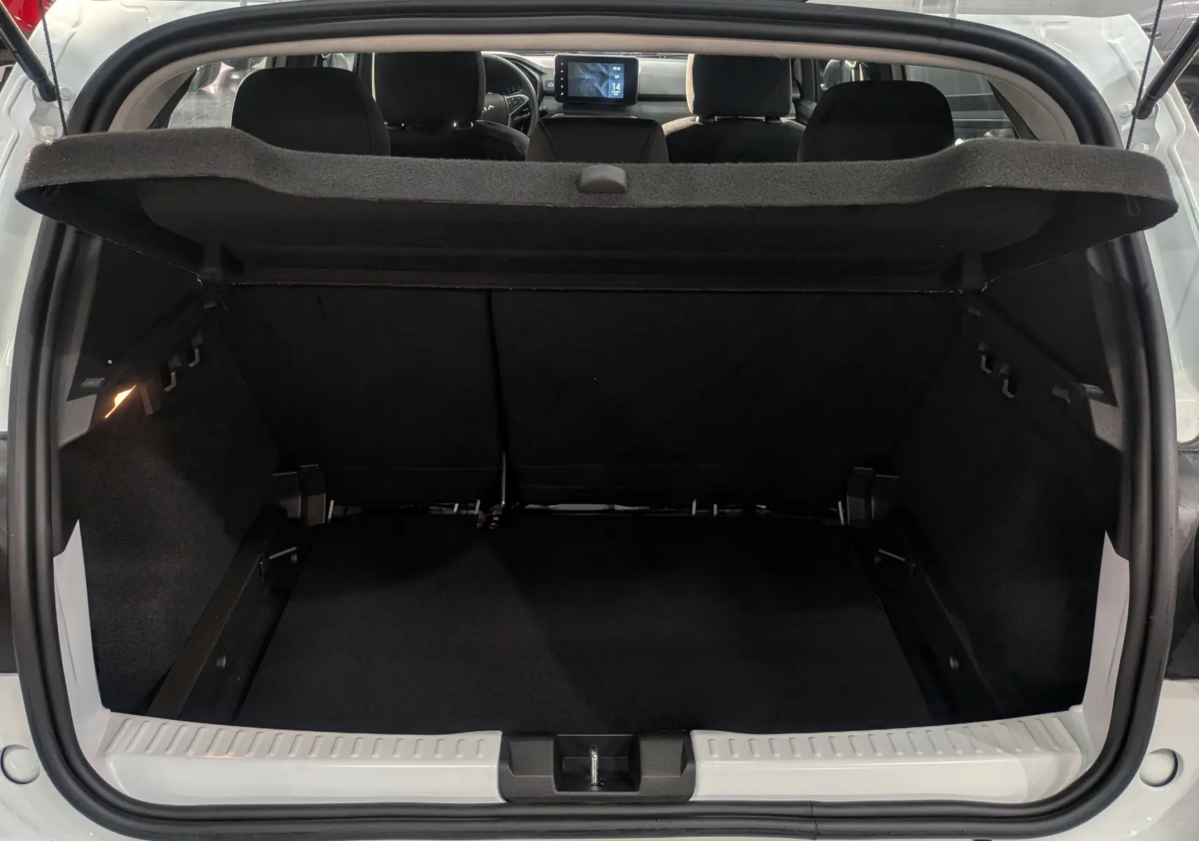 Vue depuis le coffre ouvert d'une Dacia Sandero Stepway blanc glacier, montrant l'espace de chargement et l'intérieur noir.