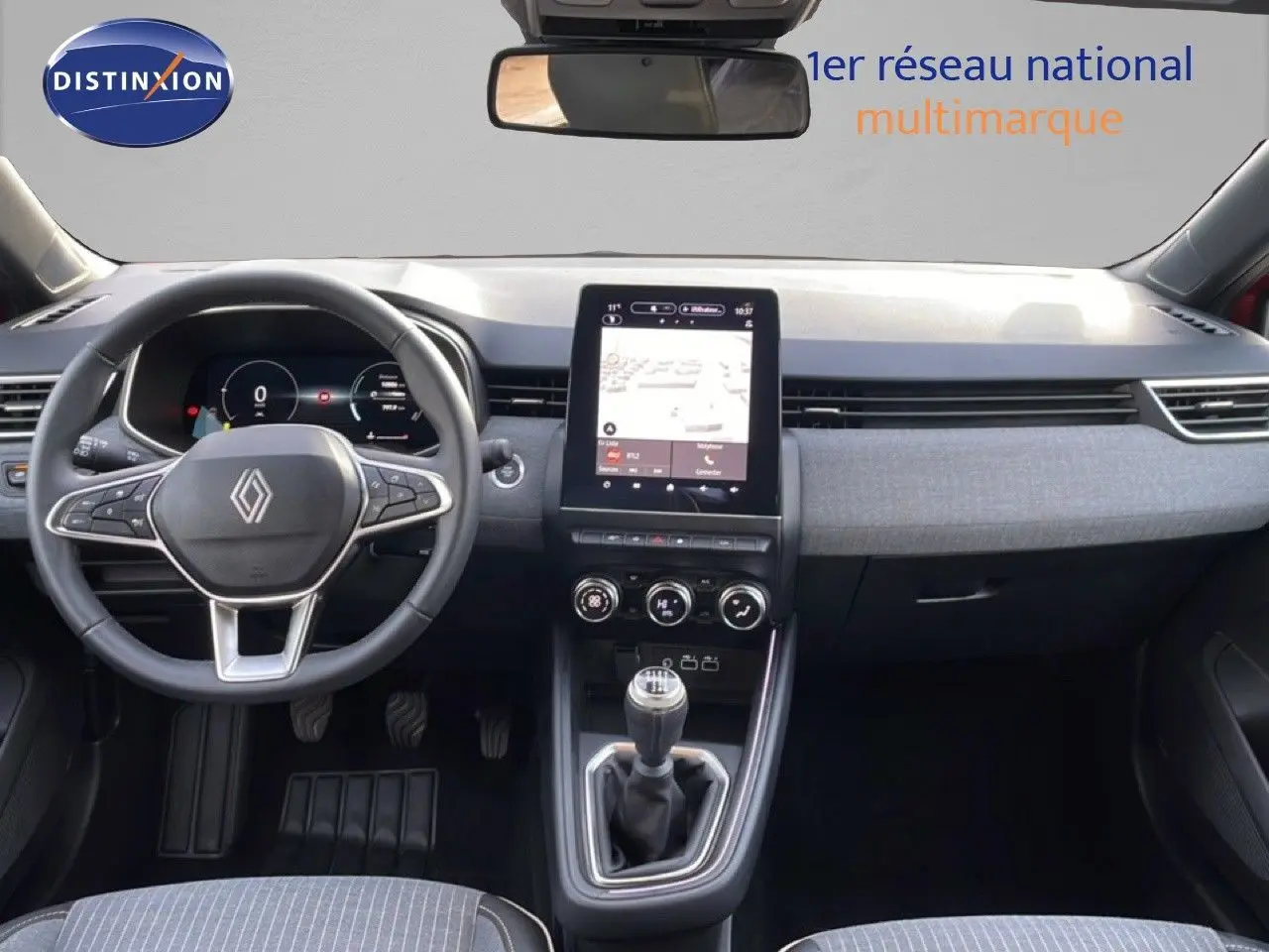 Vue intérieure avant de la Renault Clio 2025, tableau de bord moderne avec écran tactile vertical et levier de vitesse manuel.