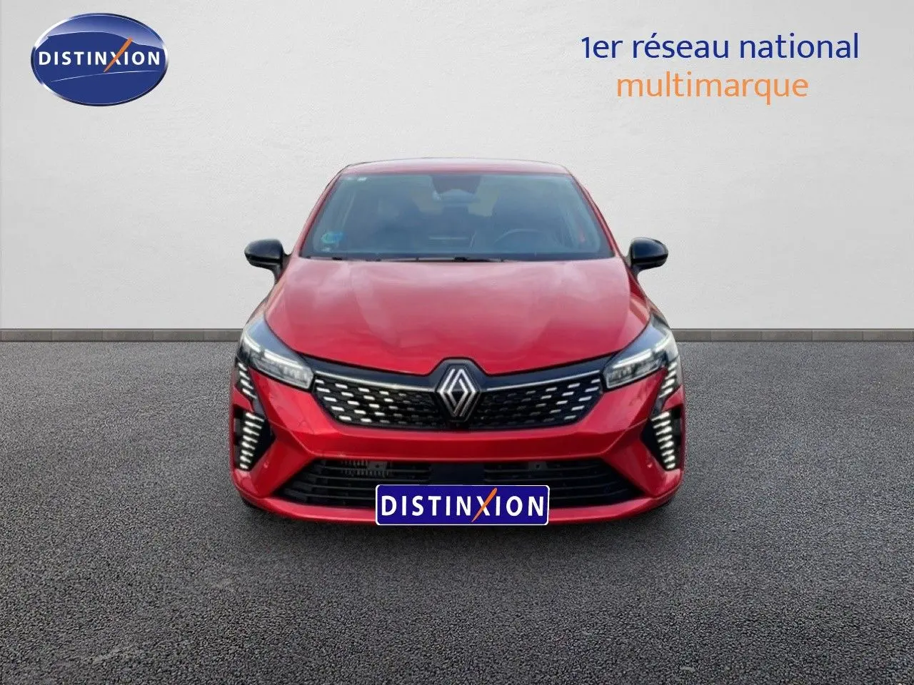 Vue frontale d'une Renault Clio 2025 rouge désir métal avec calandre noire et feux LED distinctifs allumés.