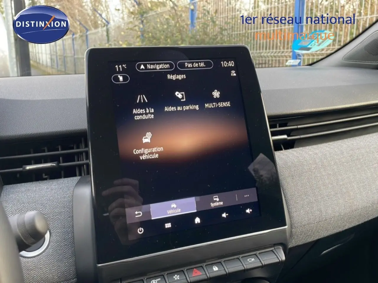 Écran tactile central en gros plan dans l’habitacle d’une Renault Clio rouge Désir Métal 2025, affichant les réglages du véhicule.