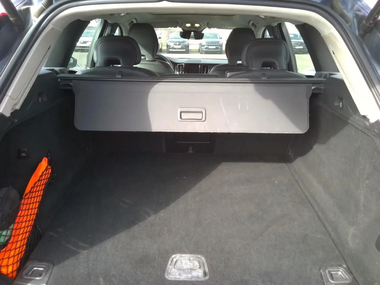 Vue arrière du coffre spacieux d'un Volvo XC60 2023, intérieur sombre avec cache-bagages déployé.