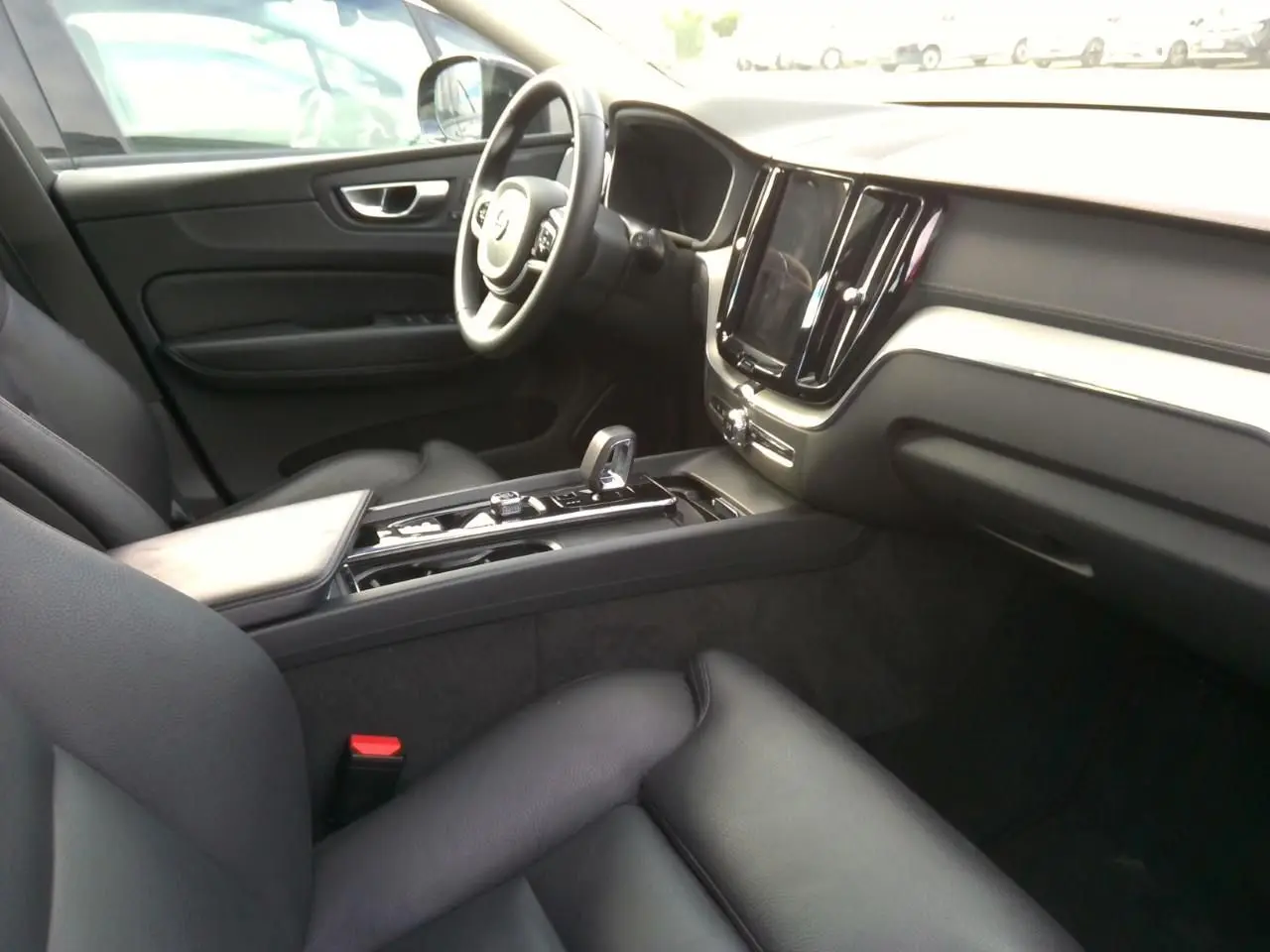 Vue intérieure côté passager du Volvo XC60 2023, avec tableau de bord noir et console centrale moderne.