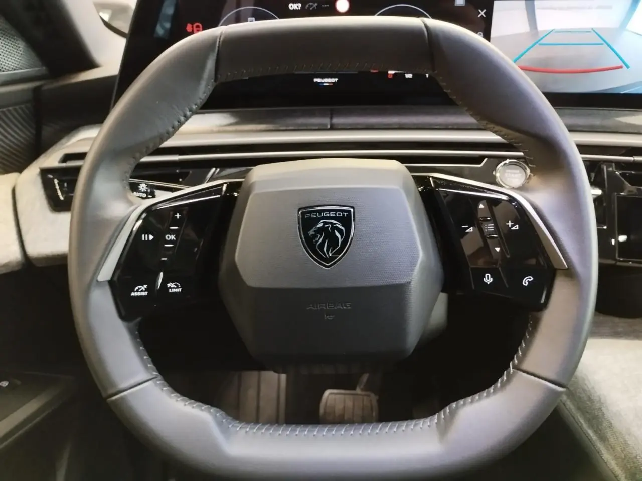 Vue rapprochée du volant cuir gris du Peugeot 3008 2024 avec logo lion et commandes intégrées noir laqué.