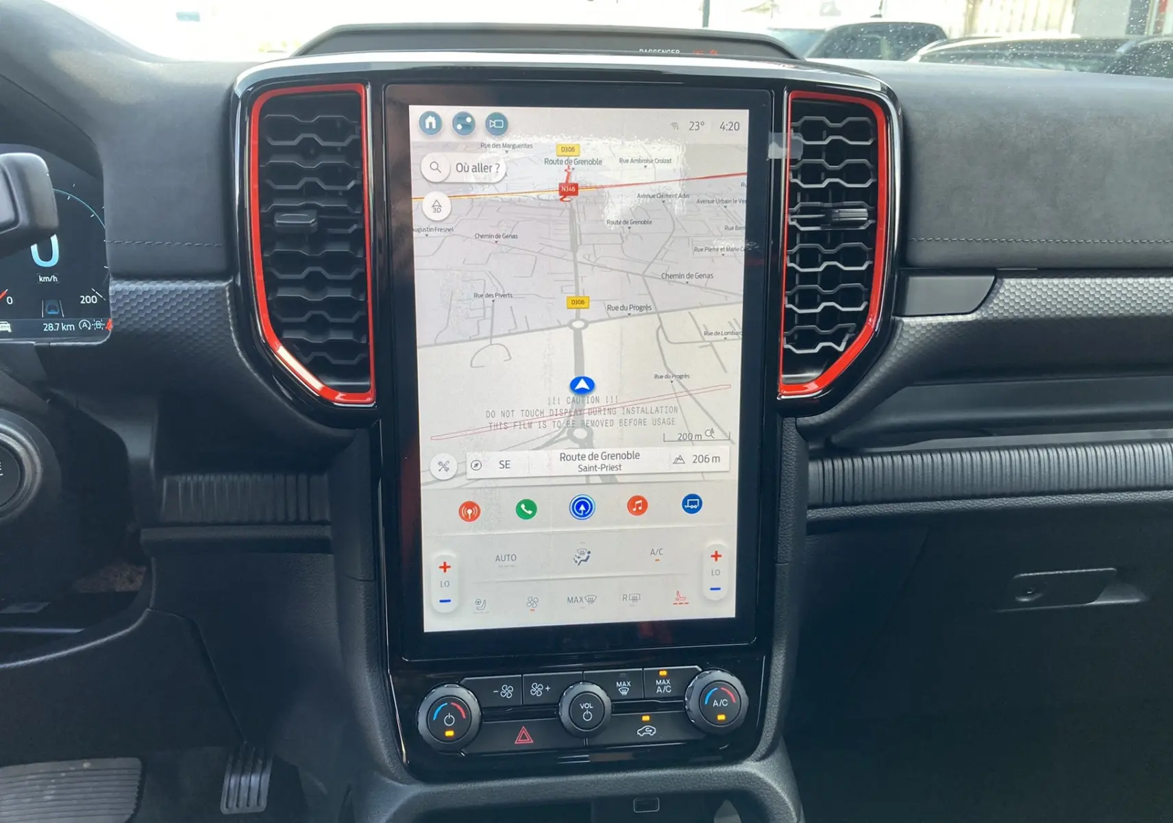 Vue centrale du tableau de bord du Ford Ranger Raptor 2026 avec écran tactile vertical et finitions rouges autour des aérateurs.