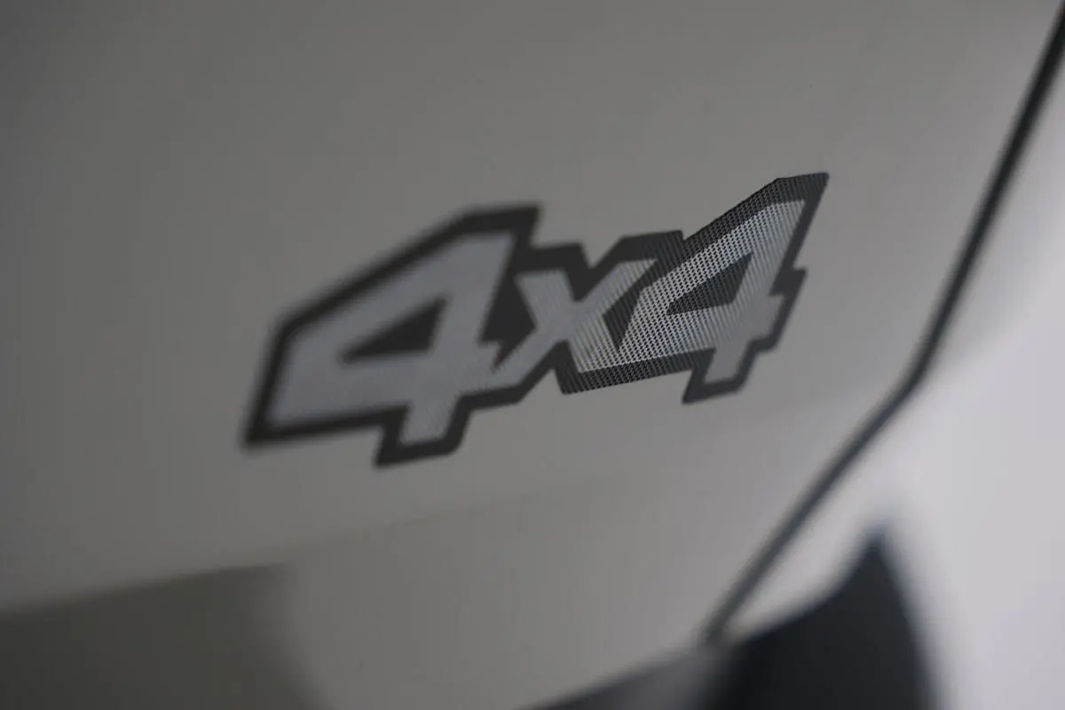 Gros plan sur l’inscription 4x4 en noir et gris sur la carrosserie couleur Sandstone du Dacia Duster 2024.