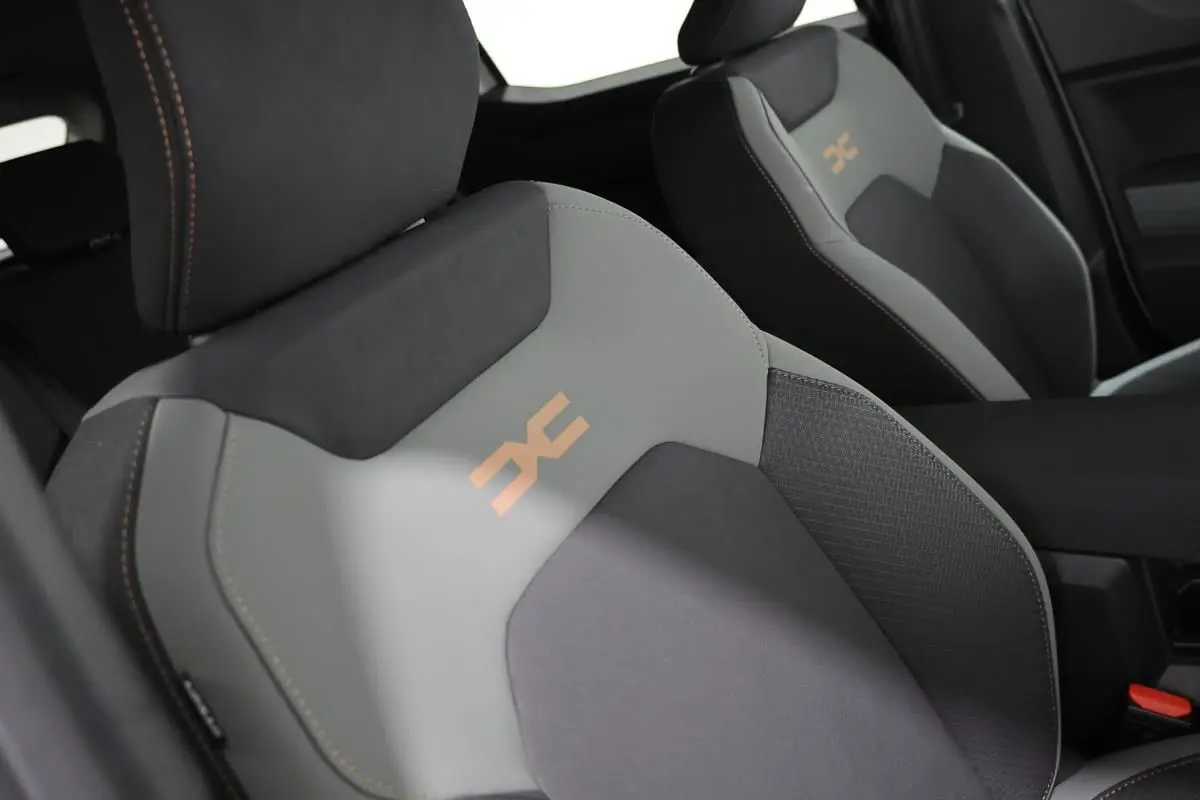 Gros plan sur les sièges avant gris et noirs du Dacia Duster 2024 avec logo orange et surpiqûres contrastées.