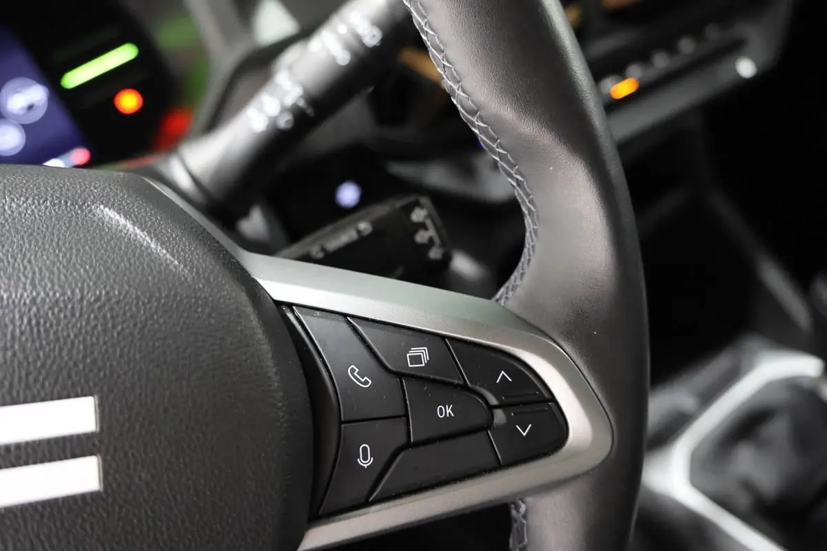 Gros plan sur le volant en cuir noir du Dacia Duster 2024, montrant les commandes multifonctions côté droit.