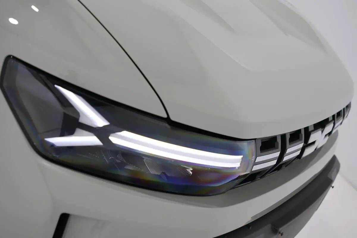 Gros plan sur le phare avant gauche et la calandre du Dacia Duster 2024 couleur Sandstone.