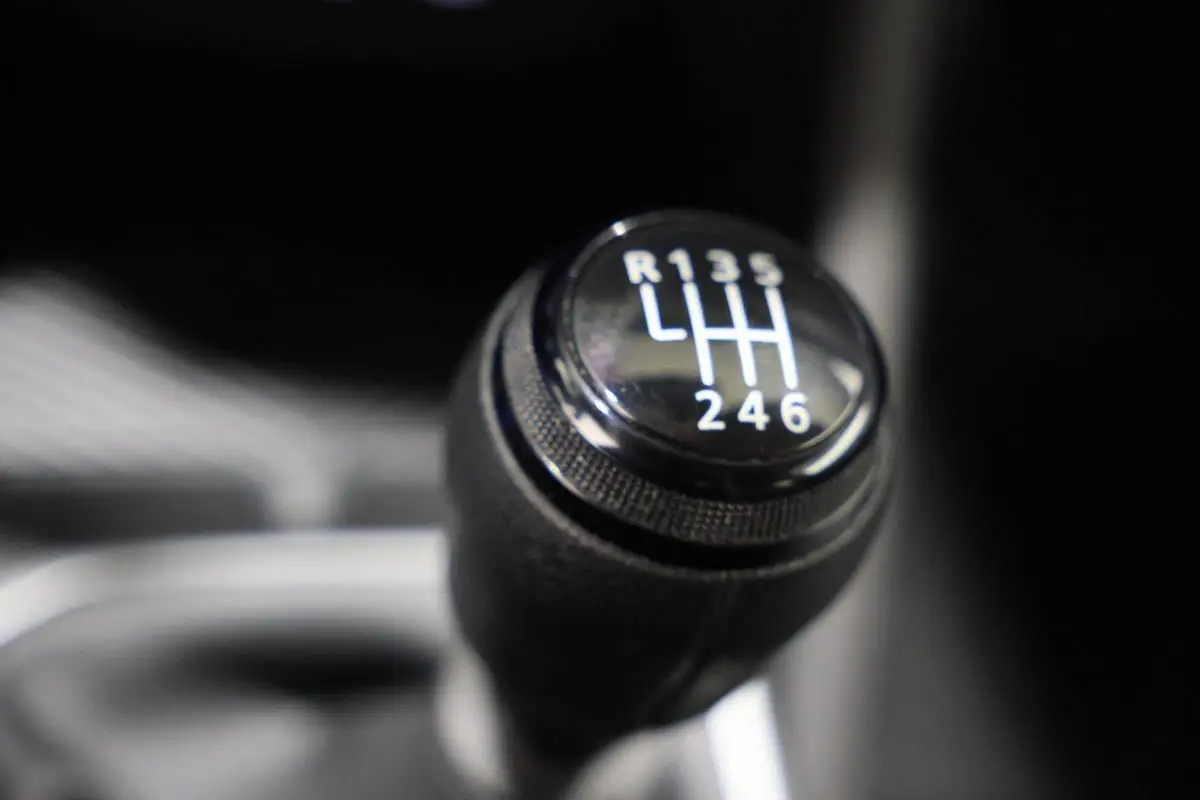 Gros plan sur le levier de vitesses manuel du Dacia Duster TCE 130 4x4, intérieur sombre.