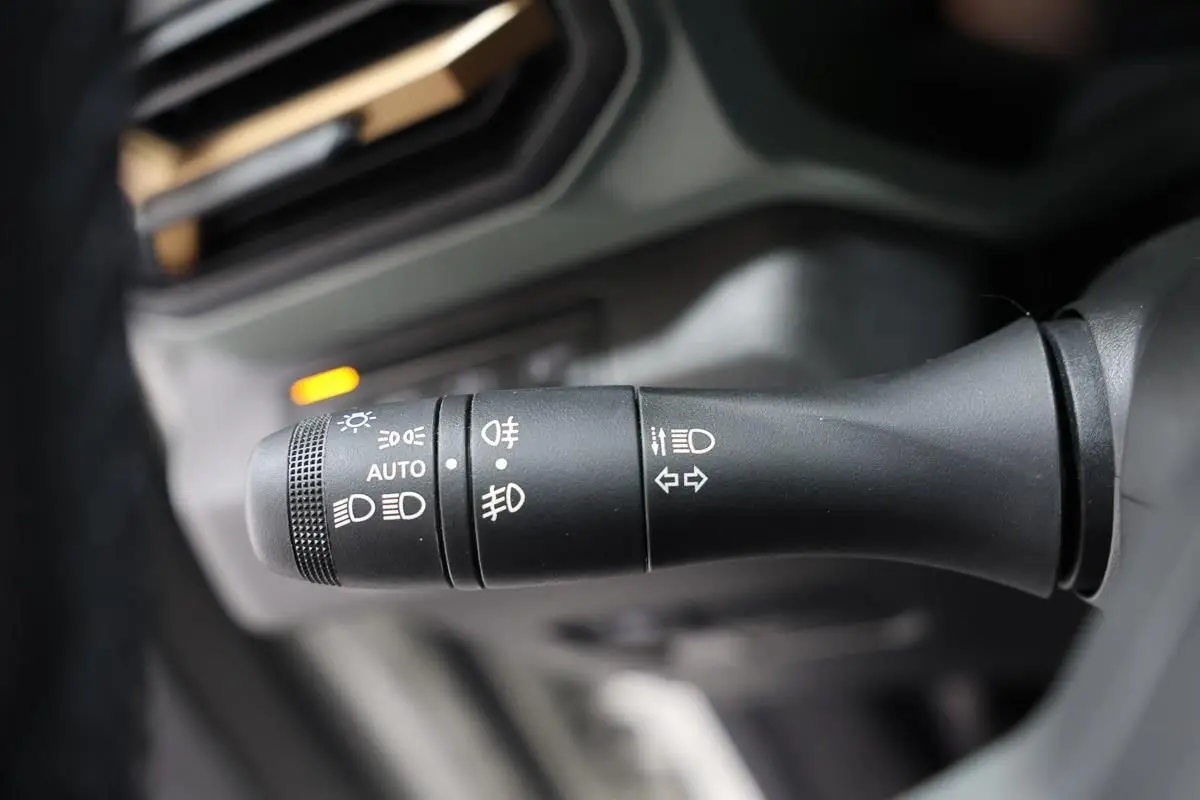 Gros plan sur la commande des phares et clignotants du Dacia Duster 2024, intérieur noir.