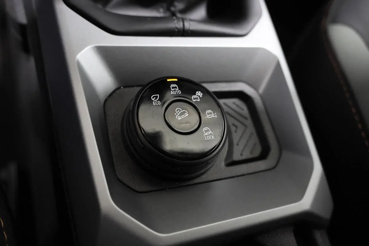 Gros plan sur la molette de sélection des modes de conduite du Dacia Duster TCE 130 4x4, intérieur gris et noir.