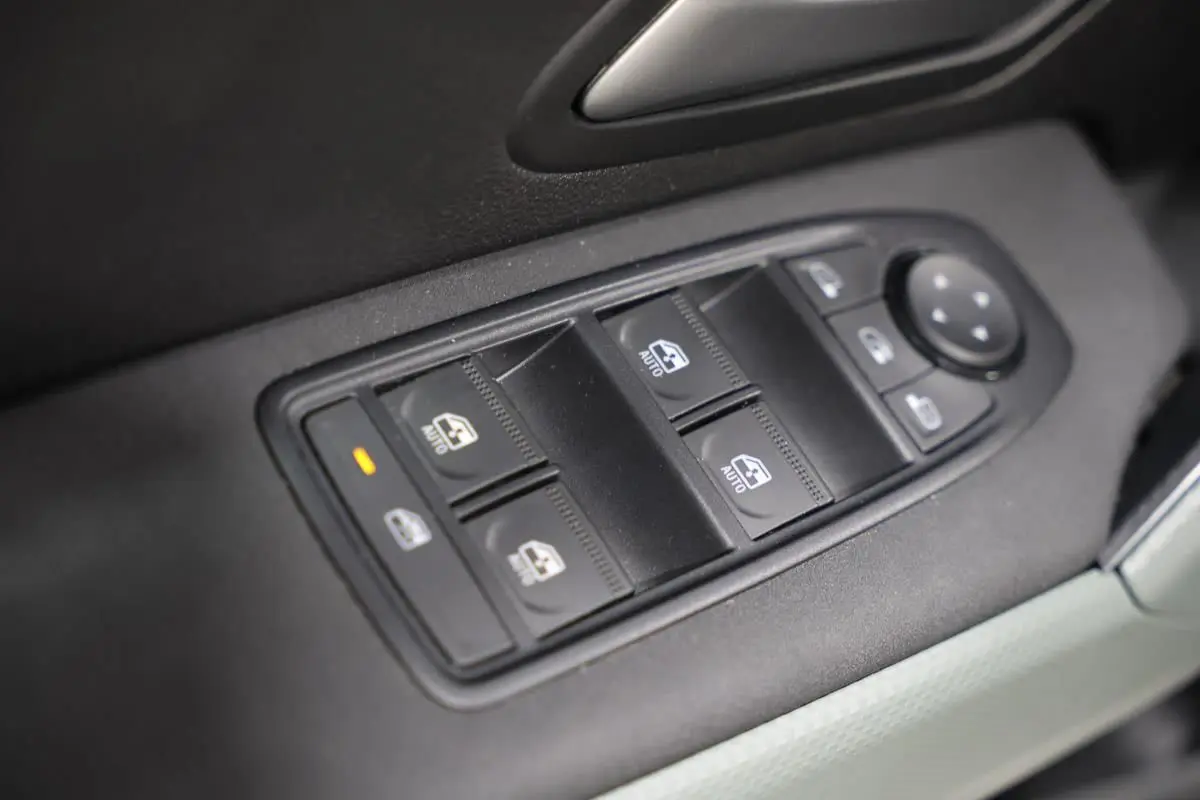Gros plan sur les commandes de lève-vitres et réglage des rétroviseurs intérieures du Dacia Duster 2024.