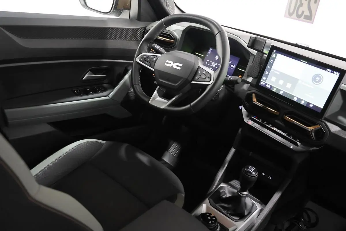 Vue intérieure côté conducteur du Dacia Duster 2024 avec volant multifonction et écran tactile central.