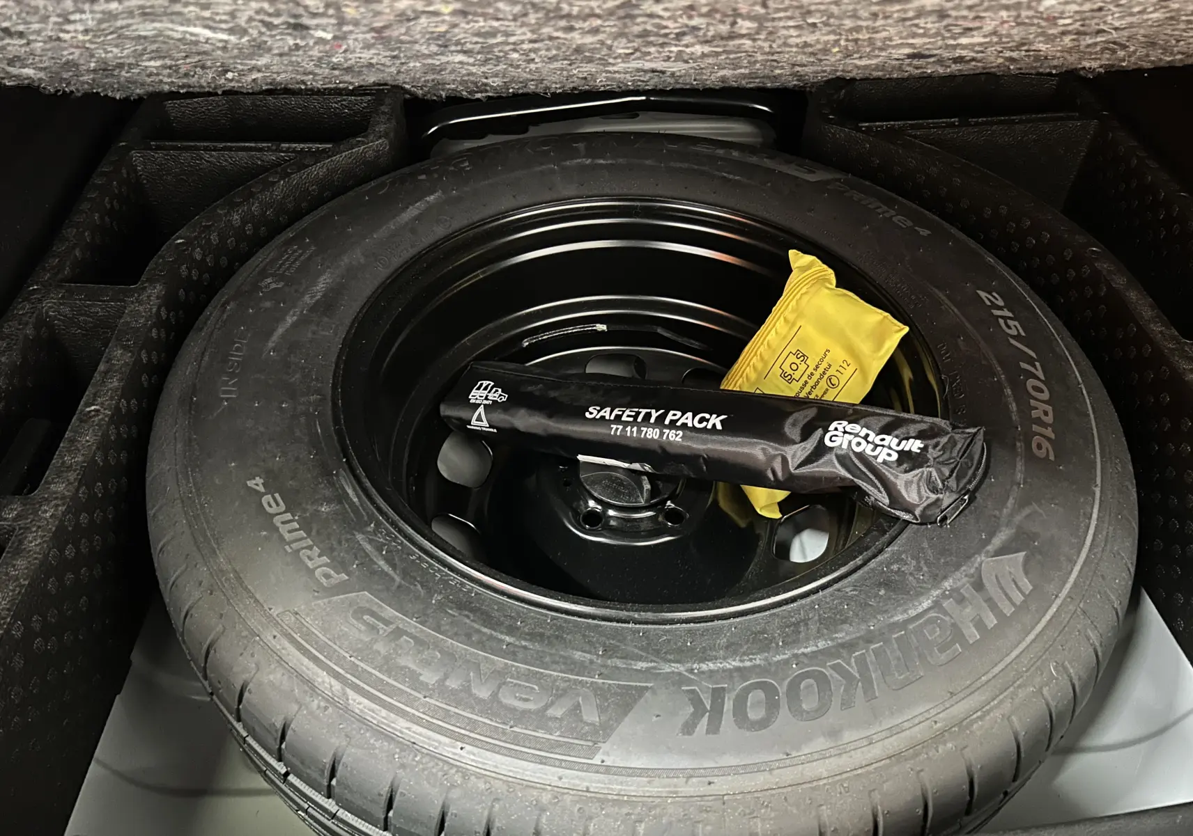 Gros plan sur la roue de secours Hankook dans le coffre du Dacia Duster 2024, avec kit de sécurité Renault posé dessus.