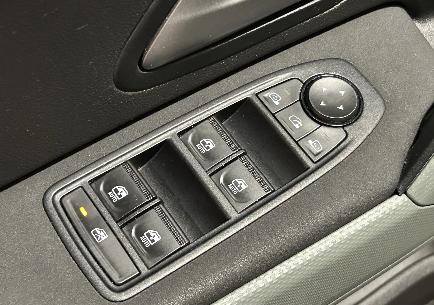 Gros plan sur les commandes électriques des vitres et rétroviseurs côté conducteur du Dacia Duster 2024 couleur Sandstone.