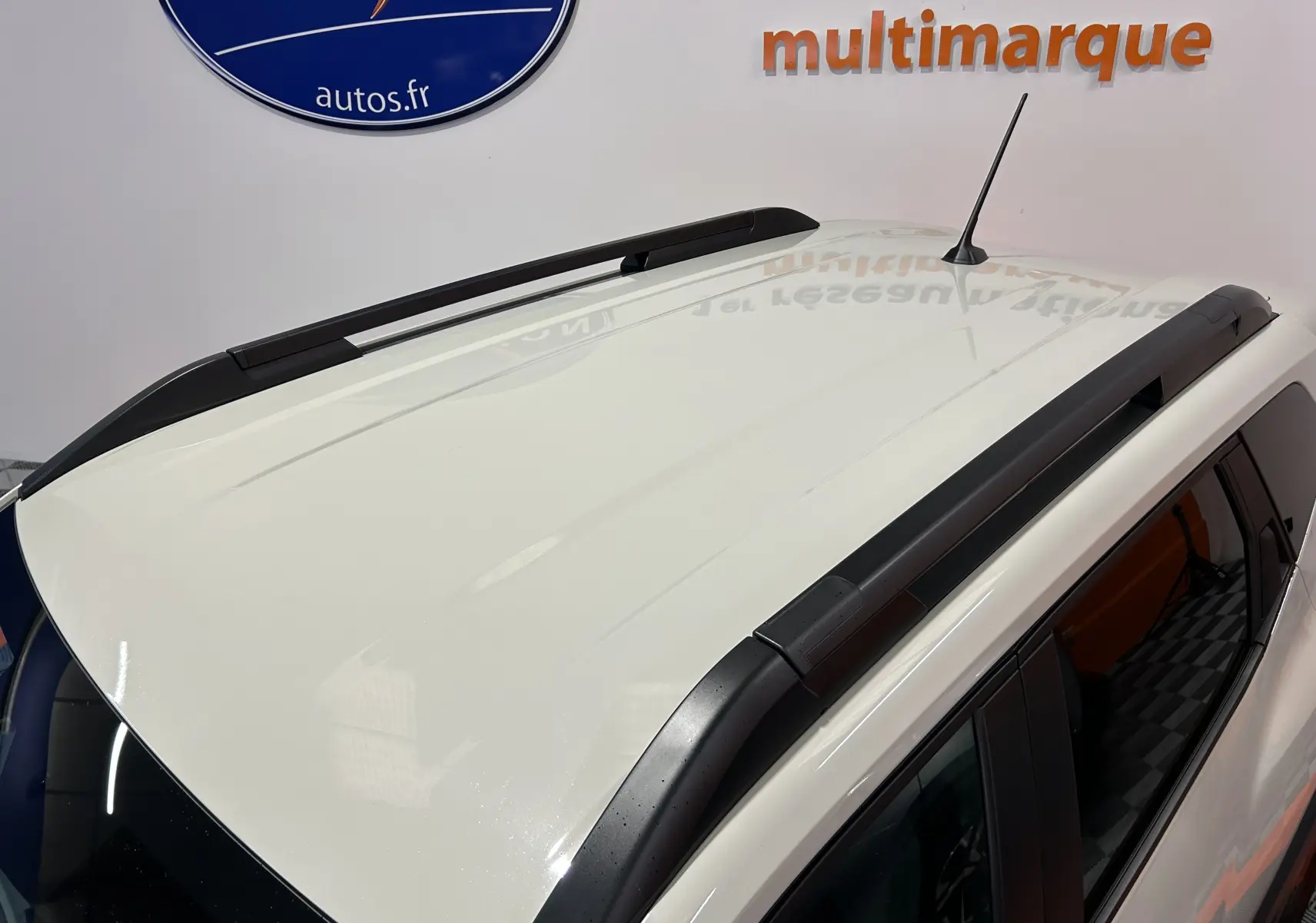Vue en plongée du toit blanc du Dacia Duster 2024 avec barres de toit noires et antenne centrale.